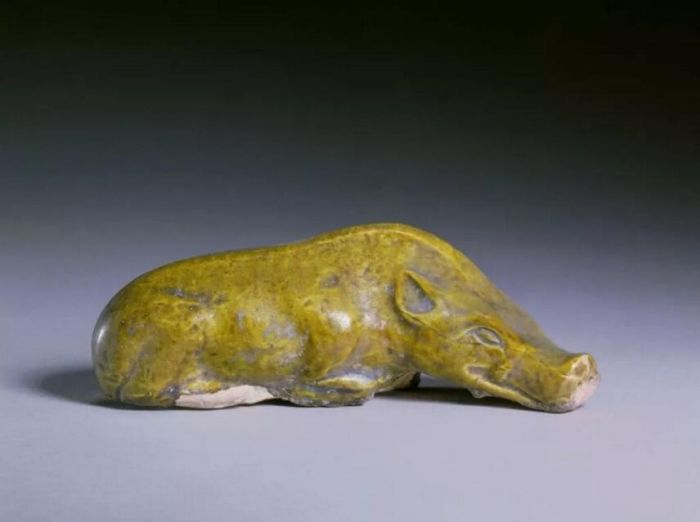 ▲隋 深黄釉卧猪 长13.2cm、宽4.5cm、高4.5cm 故宫博物院藏
