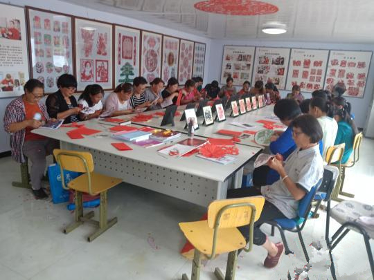 村民在非遗扶贫就业工坊练习剪纸